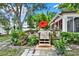 Cozy back deck with dining set, red umbrella, and lush landscaping creating a private outdoor living space at 10732 Drummond Rd, Tampa, FL 33615