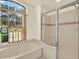 Bathroom with a soaking tub, glass-enclosed shower, and large arched window with decorative glass at 10732 Drummond Rd, Tampa, FL 33615