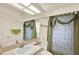 Well-lit bathroom features a single sink, green accents, and shower with a patterned curtain at 10732 Drummond Rd, Tampa, FL 33615