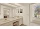 Bathroom featuring double sinks, large mirrors, vanity lighting, and a separate bathtub room with an arched stained-glass window at 10732 Drummond Rd, Tampa, FL 33615