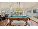 Bright game room featuring a stylish pool table with hanging light fixture and views of the lush outdoors at 10732 Drummond Rd, Tampa, FL 33615