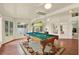 This bright game room boasts a stylish pool table with unique hanging light fixture and surrounding windows at 10732 Drummond Rd, Tampa, FL 33615