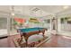Bright game room featuring a stylish pool table with hanging light fixture and views of the outdoor deck at 10732 Drummond Rd, Tampa, FL 33615