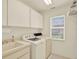 Bright laundry room with white cabinets, a sink, modern washer and dryer at 10732 Drummond Rd, Tampa, FL 33615