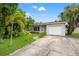 Single-story home featuring an attached garage and a beautifully landscaped front yard with mature palms and trees at 1084 39Th Ne Ave, St Petersburg, FL 33703