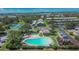 Aerial view of community amenities: a sparkling pool, playground, tennis court, and verdant landscaping at 110 114Th Ne Ter # 110, St Petersburg, FL 33716