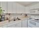 Close-up of an efficient kitchen area with white cabinets, dishwasher, and a microwave at 110 114Th Ne Ter # 110, St Petersburg, FL 33716