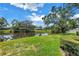 A serene backyard view of the home and the calming pond with lush green grass at 11250 Tradewinds Blvd, Largo, FL 33773