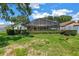 Rear exterior view of home with a screened-in pool area, green lawn, and mature landscaping at 11250 Tradewinds Blvd, Largo, FL 33773