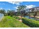 A gorgeous pool enclosed with a screened cage, manicured shrubs, and lush green lawn at 11250 Tradewinds Blvd, Largo, FL 33773