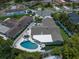 Aerial view of backyard featuring a swimming pool, patio set, pristine landscaping, and artificial turf at 11763 Saree Ct, Largo, FL 33778