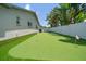 Backyard with putting green, artificial grass, palm trees, and a white privacy fence at 11763 Saree Ct, Largo, FL 33778