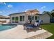 Outdoor pool with 2 blue lounge chairs, white pavers, umbrella, grass, and the rear of the house at 11763 Saree Ct, Largo, FL 33778