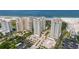 Aerial view features several beachfront condos with parking, landscaped grounds, and tennis courts by the beach at 1180 Gulf Blvd # 504, Clearwater Beach, FL 33767