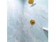 Close-up of a modern shower with stylish blue and gold marble-look tiles and gold fixtures at 1180 Gulf Blvd # 504, Clearwater Beach, FL 33767