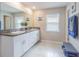 Bright bathroom with granite countertop, double sinks, white cabinetry, and tile flooring at 13527 Willow Bluestar Loop, Riverview, FL 33579