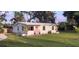 Charming single-story home featuring a well-manicured lawn, a pastel exterior, and a welcoming pink front door at 1407 Coral Ridge Dr, Punta Gorda, FL 33950