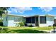 Rear exterior view highlighting a screened in porch, windows with blinds, and a well maintained lawn at 1407 Coral Ridge Dr, Punta Gorda, FL 33950