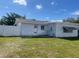 Backyard view of a white house, white fence, grassy area, and blue sky at 1480 Fairfield Dr, Clearwater, FL 33764
