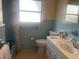 Bathroom featuring blue tile, vanity, toilet, and window for natural light at 1480 Fairfield Dr, Clearwater, FL 33764