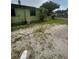 View of the backyard, with a mix of grass and gravel, showing the home's exterior and surrounding vegetation at 1557 15Th S St, St Petersburg, FL 33705
