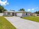 Charming single-story home with a well-manicured lawn and a long driveway leading to an attached garage at 1675 E Grovehill Rd, Palm Harbor, FL 34683
