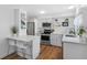 Modern white kitchen with stainless steel appliances, quartz countertops, and a breakfast bar at 1675 E Grovehill Rd, Palm Harbor, FL 34683