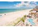 An elevated view of a white sandy beach, clear blue ocean waters, and a luxurious pool area at 17720 Gulf Blvd # A702, Redington Shores, FL 33708