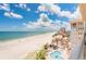 An elevated view of a white sandy beach and clear blue ocean waters, plus a pool and city view at 17720 Gulf Blvd # A702, Redington Shores, FL 33708