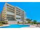 Enjoy the refreshing community pool with ample lounge space, palm trees, and stunning views of the beachfront condo building at 17720 Gulf Blvd # A702, Redington Shores, FL 33708
