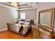 Stylish primary bedroom features tray ceiling, hardwood floors and a large dresser with mirror at 18439 Red Willow Way, Land O Lakes, FL 34638