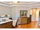 Stylish primary bedroom features tray ceiling, hardwood floors and a large dresser with mirror at 18439 Red Willow Way, Land O Lakes, FL 34638