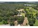 Aerial view shows home and outbuildings with mature trees on acreage in a serene rural setting at 2610 Crestview Rd, Wimauma, FL 33598