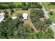 Aerial view of a metal home and outbuildings surrounded by mature trees, offering privacy and space at 2610 Crestview Rd, Wimauma, FL 33598