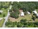 Overhead view of a property showcasing a metal home and outbuildings with mature trees along a quiet street at 2610 Crestview Rd, Wimauma, FL 33598