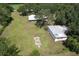 Sprawling property featuring a home, metal building, and an expansive lawn surrounded by mature trees at 2610 Crestview Rd, Wimauma, FL 33598