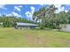 Wide backyard view showcasing a sprawling lawn, mature trees with Spanish moss, and the home's exterior at 2610 Crestview Rd, Wimauma, FL 33598