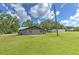 Backyard view of the home highlighting a large, grassy area and mature trees in the surrounding landscape at 2610 Crestview Rd, Wimauma, FL 33598
