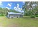 Exterior home featuring a spacious backyard with lush greenery, complemented by mature trees and a metal roof at 2610 Crestview Rd, Wimauma, FL 33598