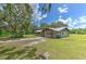 Exterior view showcasing a home with a spacious yard, long driveway, and lush trees, plus a metal roof at 2610 Crestview Rd, Wimauma, FL 33598