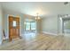 Bright living room features wood-look floors, a bay window, modern light fixture, and a detailed wooden front door at 2610 Crestview Rd, Wimauma, FL 33598