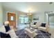 Staged living room showcases ample natural light, wood floors, and comfortable seating near a picturesque bay window at 2610 Crestview Rd, Wimauma, FL 33598