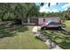 Outbuilding with a red and white truck parked nearby, situated on a large grassy lot at 2610 Crestview Rd, Wimauma, FL 33598