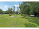 Vast backyard features lush green lawn, mature trees, partially fenced-in areas, and outdoor trailer at 26223 Chianina Dr, Wesley Chapel, FL 33544
