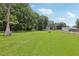 Overview of the spacious backyard with mature trees, green lawn, wood deck, and trailer at 26223 Chianina Dr, Wesley Chapel, FL 33544