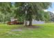 Spacious backyard with lush green grass, mature trees, wood deck, and partially fenced in area at 26223 Chianina Dr, Wesley Chapel, FL 33544