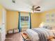 Bright bedroom showcasing yellow walls, wood floors, a ceiling fan, and a window overlooking the backyard at 26223 Chianina Dr, Wesley Chapel, FL 33544