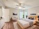 Stylishly decorated bedroom features hardwood floors, a ceiling fan, and a cozy sitting area near large windows at 26223 Chianina Dr, Wesley Chapel, FL 33544