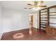 Bedroom features white walls, wood-look floors, ceiling fan, and a wooden bookcase at 26223 Chianina Dr, Wesley Chapel, FL 33544
