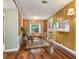 Cozy dining room featuring wood paneling, hardwood floors, a modern light fixture, and views into the kitchen at 26223 Chianina Dr, Wesley Chapel, FL 33544